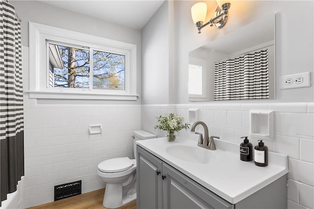 bathroom with visible vents, tile walls, a wainscoted wall, vanity, and toilet