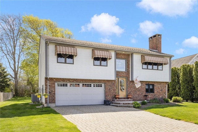 11 Renfrew Ave, Middletown, RI 02842 - split foyer home featuring a chimney, an attached garage, decorative driveway, central AC, and brick siding
