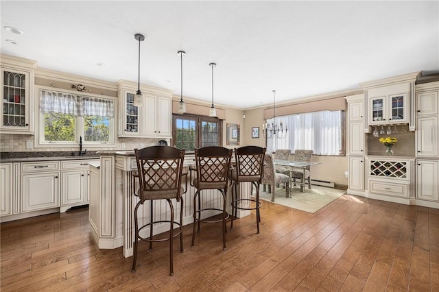 11 Renfrew Ave, Middletown, RI 02842 - kitchen featuring cream cabinetry, dark wood-style flooring, dark countertops, a kitchen island, and ornamental molding