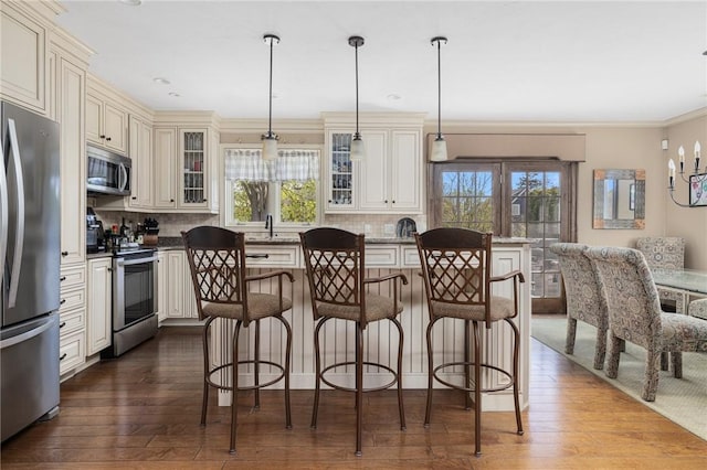 11 Renfrew Ave, Middletown, RI 02842 - kitchen featuring stainless steel appliances, cream cabinets, healthy amount of natural light, a kitchen bar, and crown molding