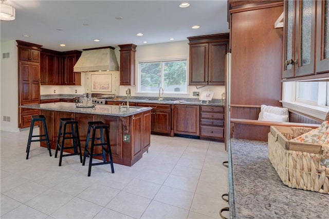 23 Pine Top Rd, Barrington, RI 02806 - kitchen with custom range hood, a breakfast bar, a center island with sink, light stone counters, and recessed lighting