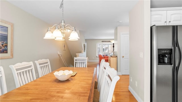 dining space featuring baseboards, light wood-style floors, and an inviting chandelier