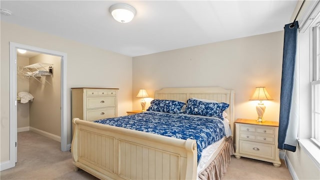 bedroom featuring light colored carpet, a closet, baseboards, and a walk in closet