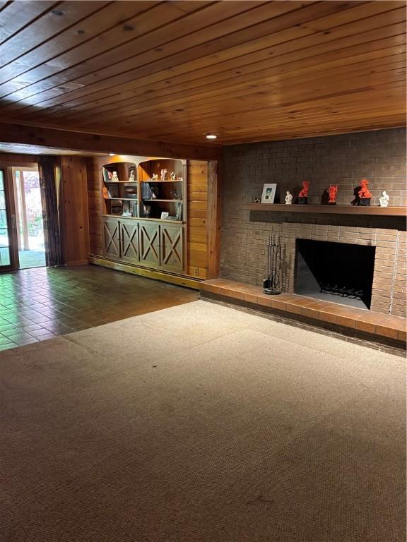 unfurnished living room featuring dark carpet, wood ceiling, and a brick fireplace