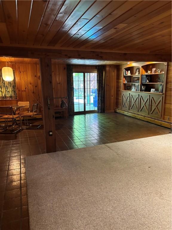 unfurnished living room with wooden walls, wooden ceiling, and a baseboard radiator