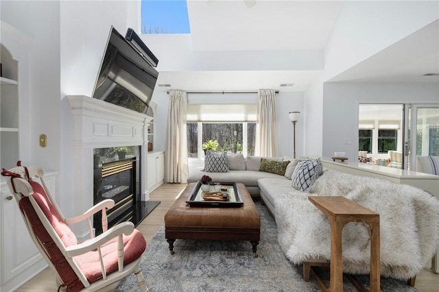 living room featuring a fireplace, light wood-style flooring, and a wealth of natural light