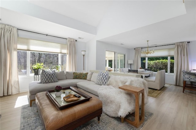living area with plenty of natural light, light wood-style flooring, a chandelier, and high vaulted ceiling