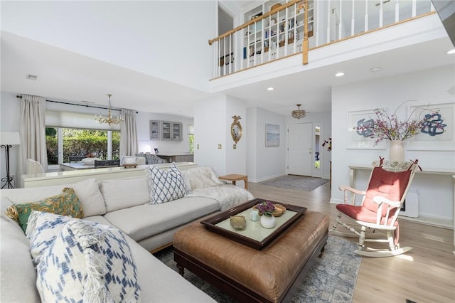 living room featuring an inviting chandelier, wood finished floors, baseboards, a high ceiling, and recessed lighting