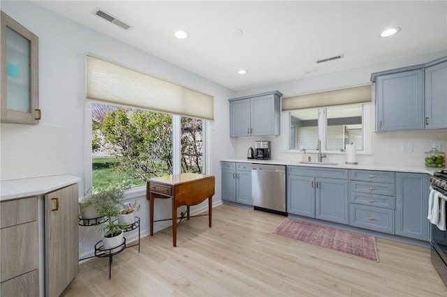 kitchen featuring stainless steel dishwasher, visible vents, a sink, and light countertops