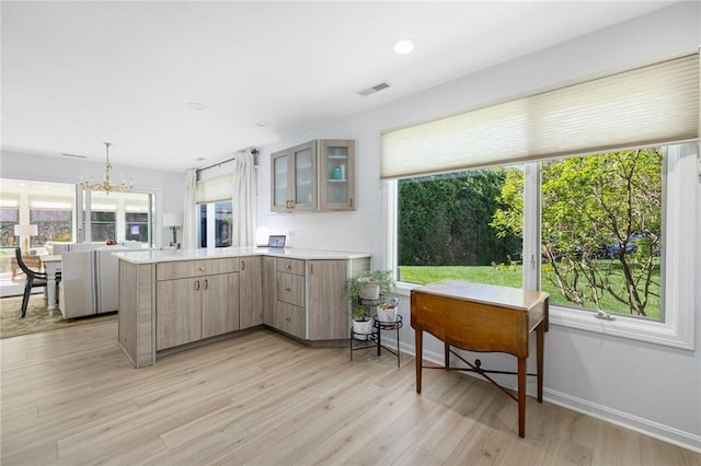 kitchen featuring glass insert cabinets, plenty of natural light, a peninsula, and visible vents