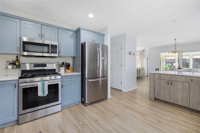 kitchen featuring an inviting chandelier, decorative backsplash, appliances with stainless steel finishes, and light countertops