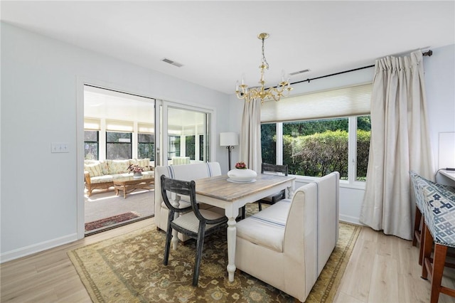 dining area featuring visible vents, light wood-style flooring, baseboards, and a notable chandelier