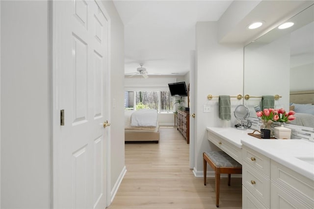 ensuite bathroom with connected bathroom, baseboards, wood finished floors, and vanity