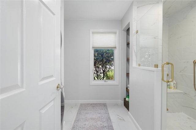 bathroom with baseboards, marble finish floor, and a stall shower