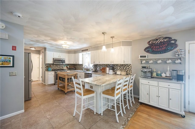 545 Central St, Burrillville, RI 02839 - kitchen featuring appliances with stainless steel finishes, a sink, decorative backsplash, a peninsula, and a kitchen breakfast bar