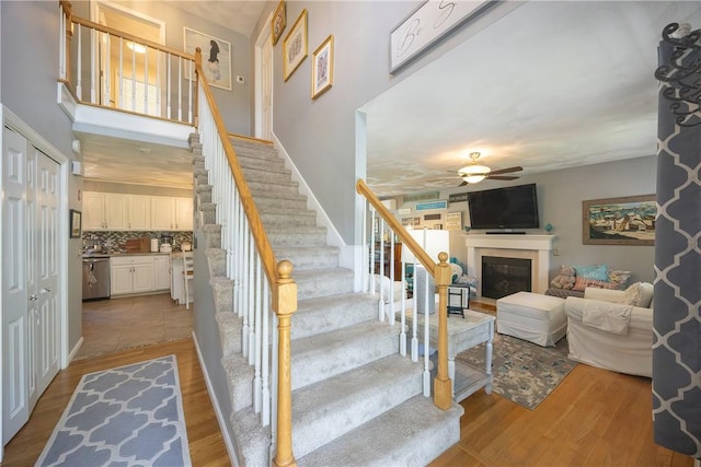 545 Central St, Burrillville, RI 02839 - staircase featuring a glass covered fireplace, ceiling fan, and wood finished floors