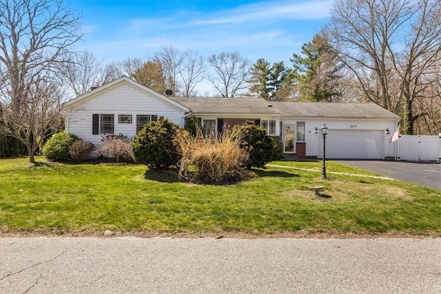 ranch-style home featuring a garage, fence, a front yard, and aphalt driveway