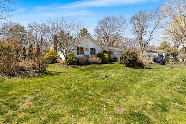 view of home's exterior with a lawn, an attached garage, and a chimney