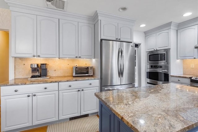 kitchen with decorative backsplash, visible vents, appliances with stainless steel finishes, a toaster, and white cabinetry
