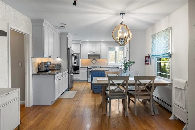 dining area featuring an inviting chandelier, plenty of natural light, baseboard heating, and light wood-style flooring