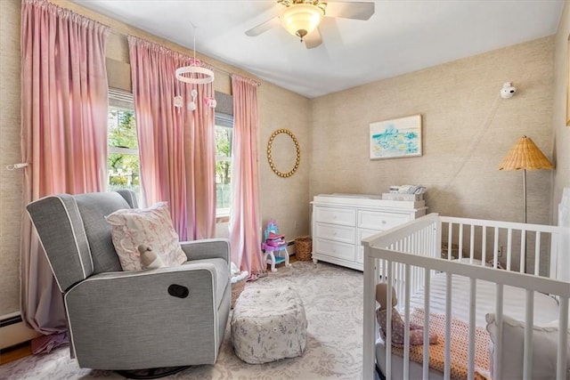 bedroom featuring a nursery area, a ceiling fan, and a baseboard radiator