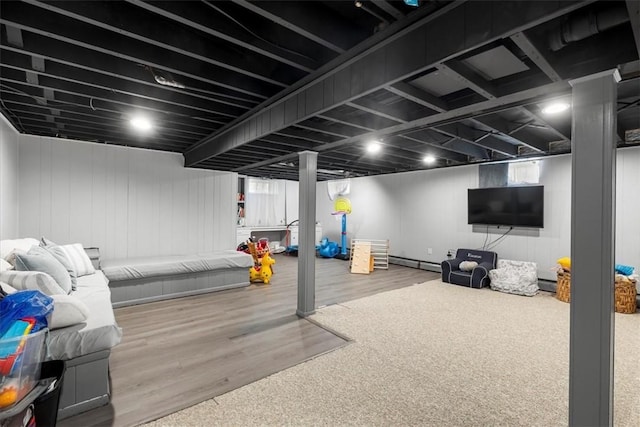 below grade area with a baseboard radiator, wood finished floors, and a wealth of natural light