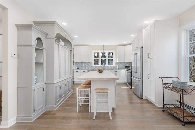 kitchen featuring a kitchen island, a breakfast bar area, light countertops, light wood-style flooring, and stainless steel appliances