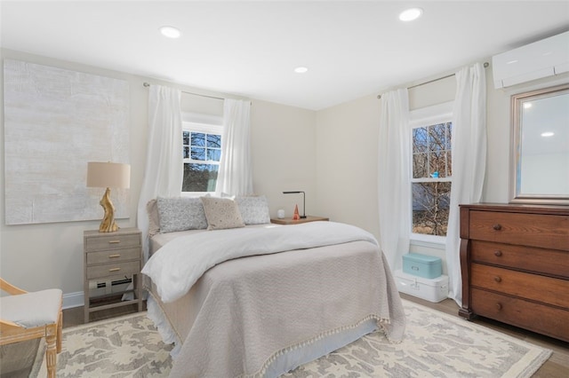 bedroom featuring recessed lighting, light wood finished floors, and a wall unit AC