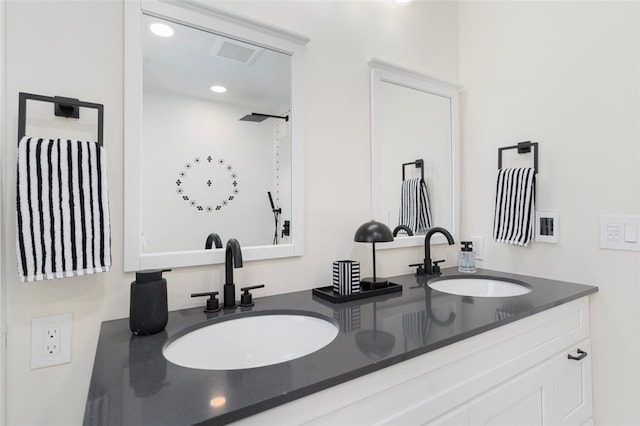 bathroom with double vanity, recessed lighting, and a sink
