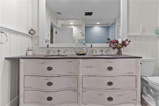 386 Stone Church Rd, Tiverton, RI 02878 - full bathroom with toilet, double vanity, a wainscoted wall, and a decorative wall