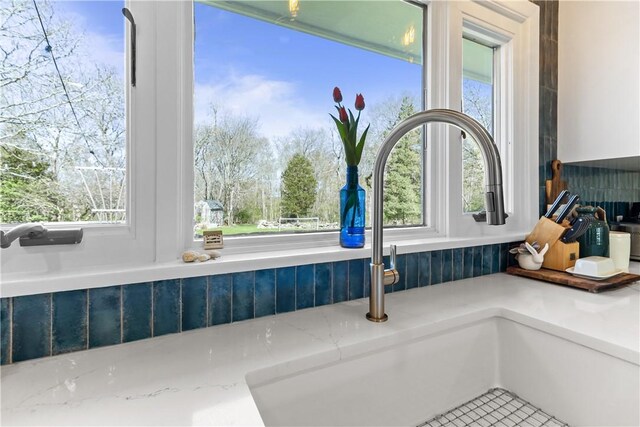 386 Stone Church Rd, Tiverton, RI 02878 - kitchen view of a sink, light stone counters, and decorative backsplash