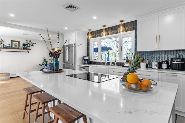 386 Stone Church Rd, Tiverton, RI 02878 - kitchen with appliances with stainless steel finishes, a sink, white cabinets, a kitchen breakfast bar, and a spacious island