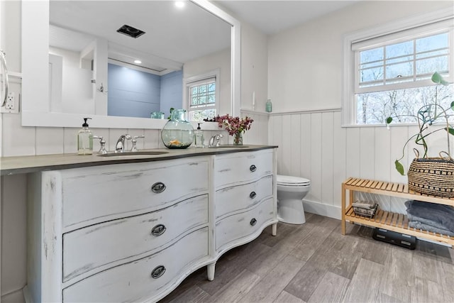 386 Stone Church Rd, Tiverton, RI 02878 - full bath featuring a wainscoted wall, toilet, double vanity, and wood finished floors