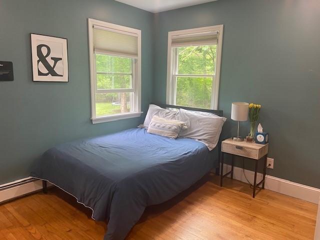 386 Stone Church Rd, Tiverton, RI 02878 - bedroom with wood finished floors, multiple windows, and baseboard heating