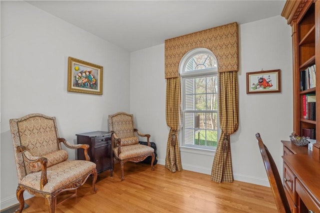 living area featuring light wood-type flooring, baseboards, and a wealth of natural light