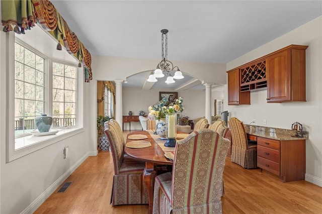 dining room with ornate columns, a wealth of natural light, and light wood-type flooring