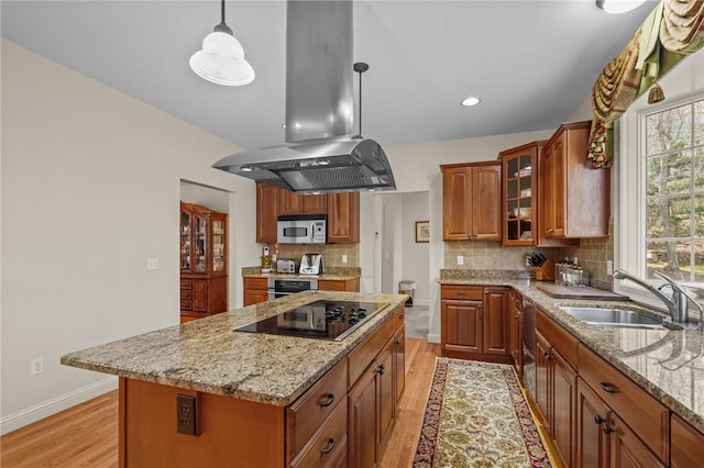 kitchen with light wood-style floors, black electric stovetop, tasteful backsplash, island exhaust hood, and a sink