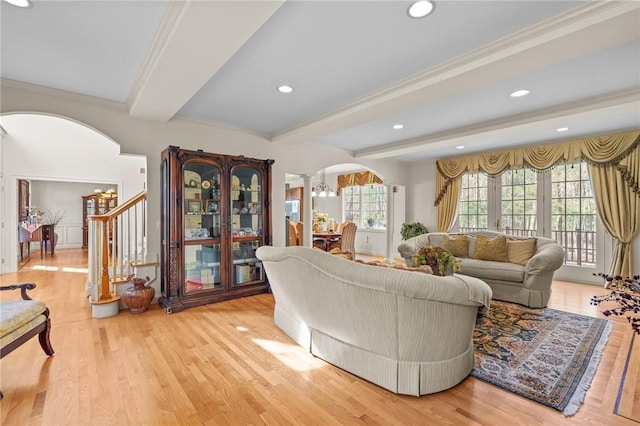 living area featuring arched walkways, beamed ceiling, an inviting chandelier, and wood finished floors