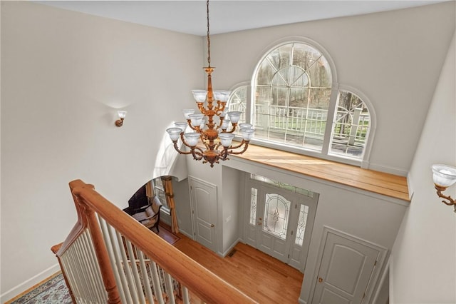 entrance foyer with baseboards, an inviting chandelier, and wood finished floors