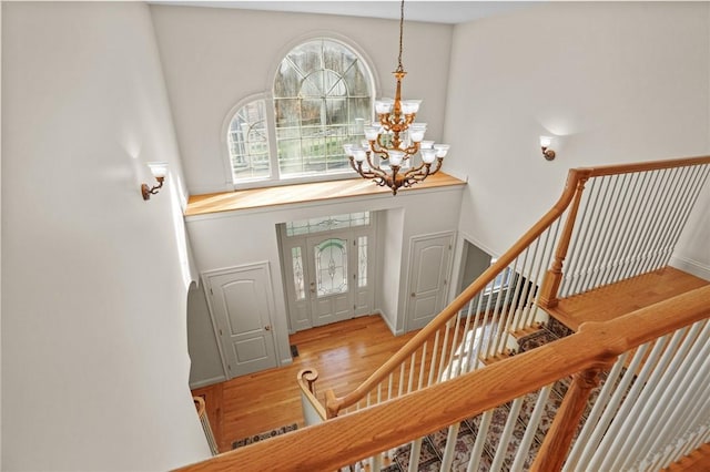 entryway with stairs, wood finished floors, baseboards, a high ceiling, and a chandelier