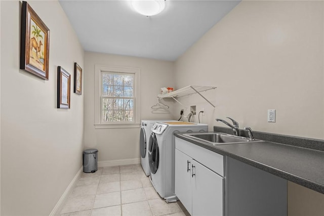 laundry area featuring washing machine and dryer, baseboards, a sink, cabinet space, and light tile patterned floors