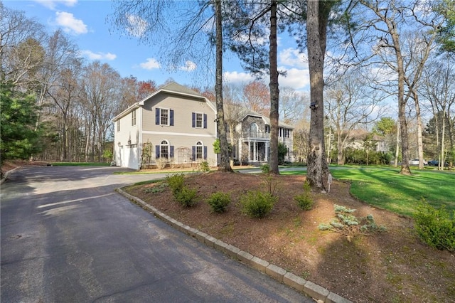 traditional-style house featuring an attached garage, a front yard, and aphalt driveway