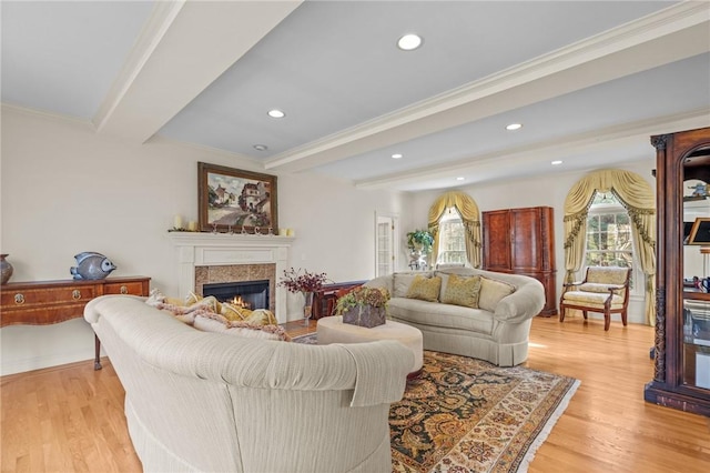 living room featuring a lit fireplace, crown molding, beamed ceiling, light wood-style floors, and recessed lighting
