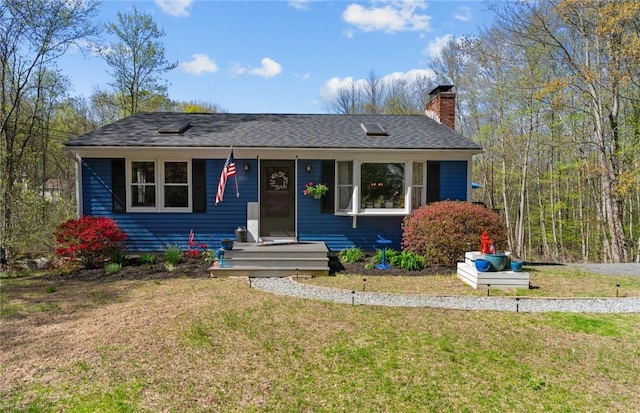 ranch-style home featuring a chimney, a front lawn, and a shingled roof