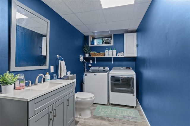 bathroom with washer and clothes dryer, wood finished floors, toilet, a drop ceiling, and vanity