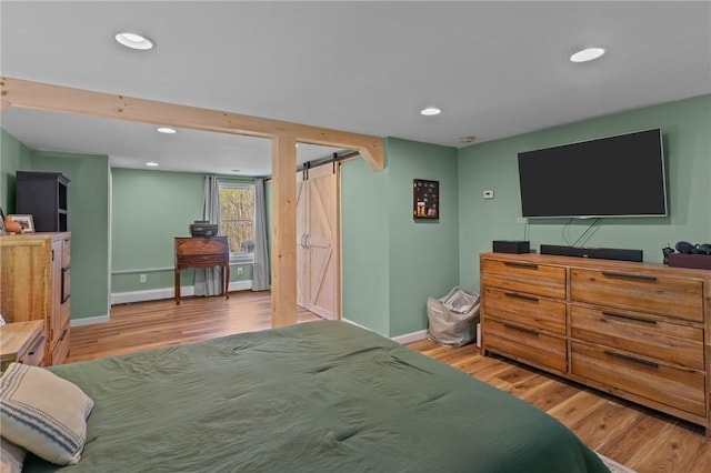 bedroom with a barn door, wood finished floors, baseboards, and recessed lighting