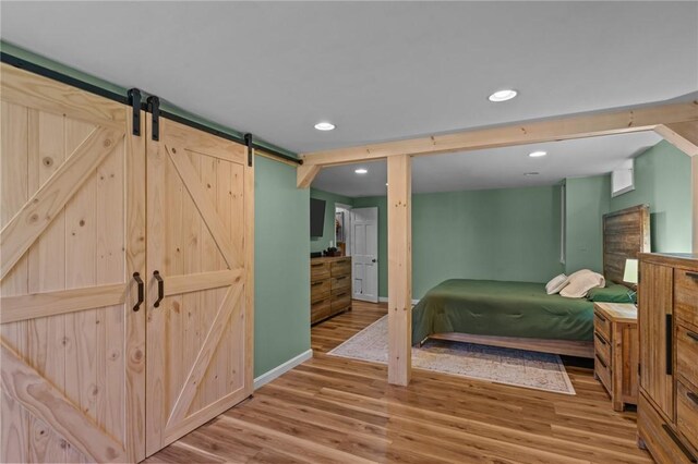 bedroom with wood finished floors, a barn door, recessed lighting, and baseboards
