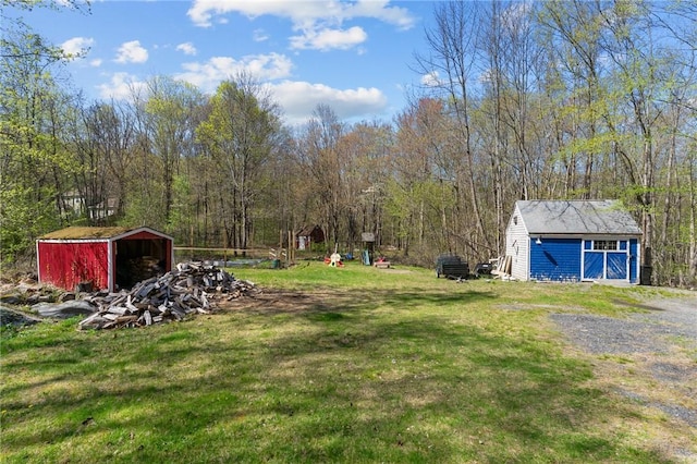 view of green lawn featuring an outdoor structure and a wooded view