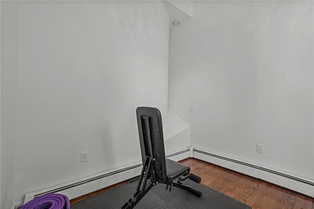 workout room featuring a baseboard heating unit and wood finished floors