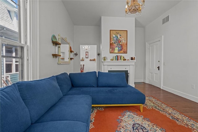 living room with a chandelier, healthy amount of natural light, wood finished floors, and baseboards